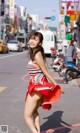 A woman in a red and white dress is walking down the street.